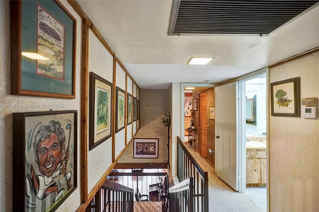 hallway with light carpet, a sink, and visible vents