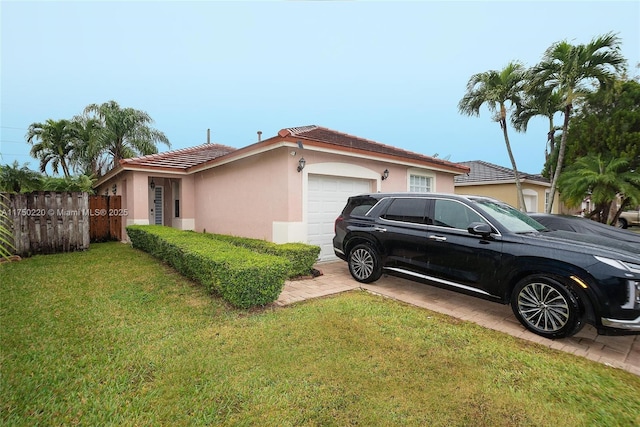 view of side of home with driveway, an attached garage, fence, a yard, and stucco siding