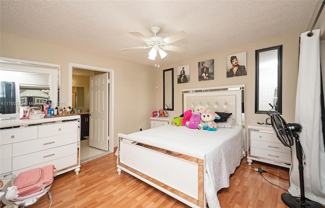 bedroom with light wood-style floors, a textured ceiling, and a ceiling fan