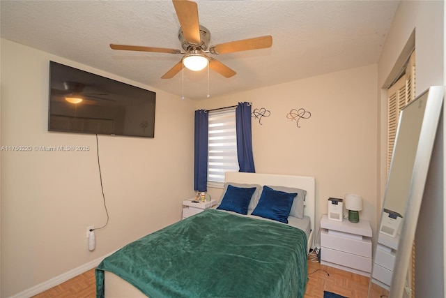 bedroom with a ceiling fan, a closet, a textured ceiling, and baseboards