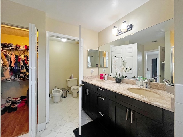 full bathroom featuring double vanity, a spacious closet, a bidet, a sink, and tile patterned flooring