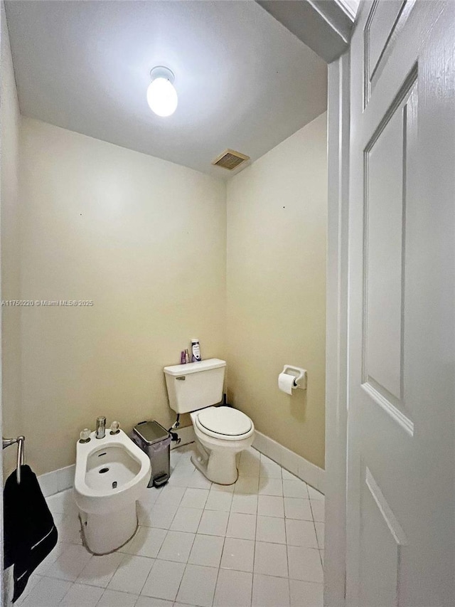 bathroom featuring toilet, tile patterned flooring, a bidet, and baseboards