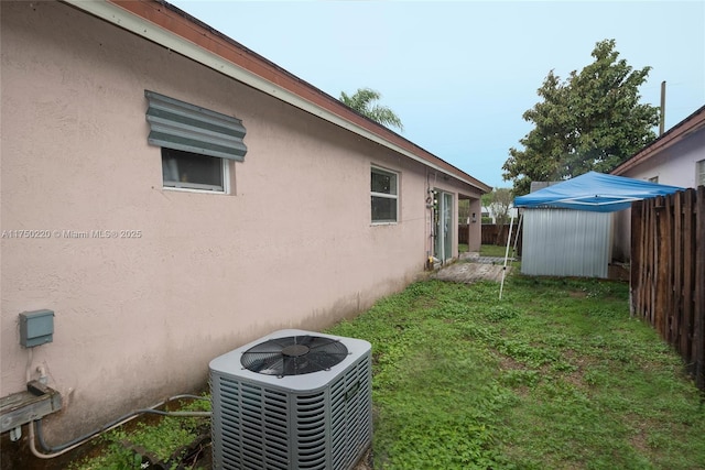 view of yard with an outbuilding, central AC, fence, and a storage unit