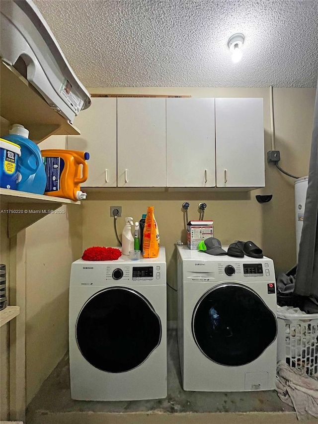 laundry area with cabinet space, a textured ceiling, and washer and dryer