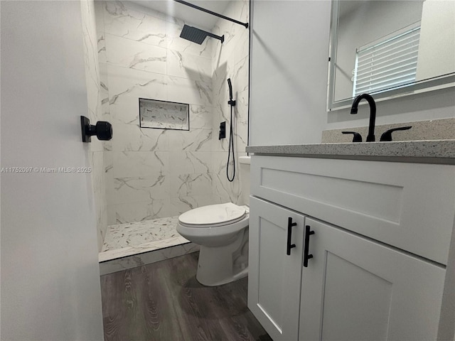 full bath featuring toilet, a marble finish shower, wood finished floors, and vanity