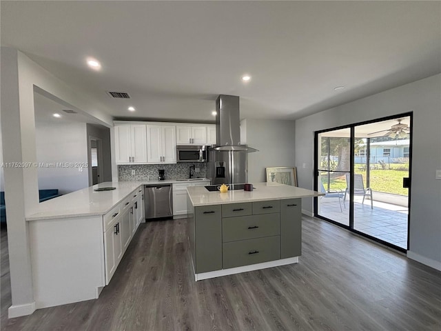 kitchen featuring tasteful backsplash, visible vents, appliances with stainless steel finishes, a kitchen island, and island range hood