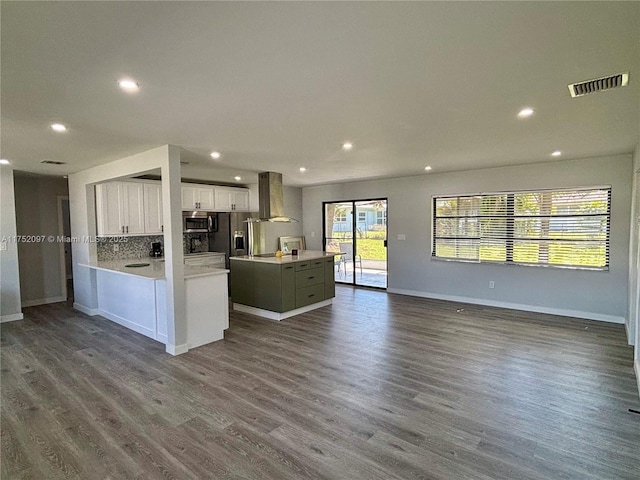 kitchen with wall chimney range hood, visible vents, open floor plan, and stainless steel microwave