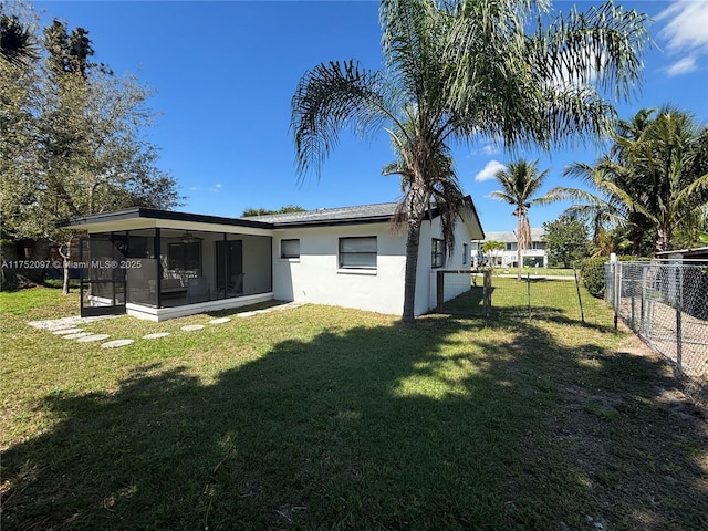 back of house featuring a fenced backyard, a sunroom, a yard, a gate, and stucco siding