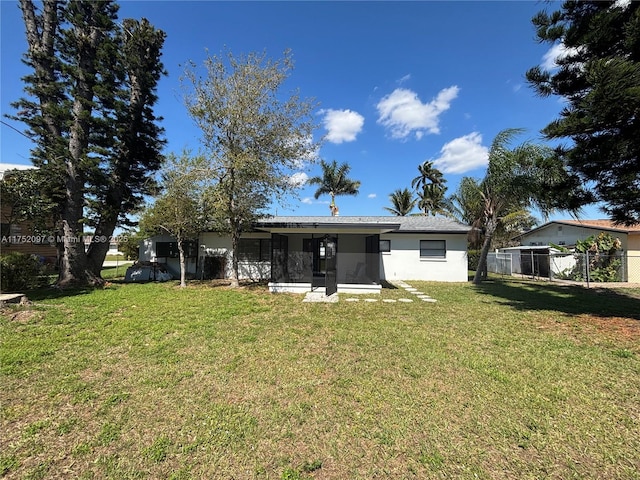 back of property with a yard, fence, a sunroom, and stucco siding