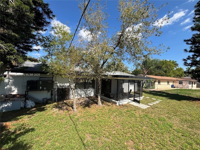 back of property featuring a sunroom, a lawn, and fence