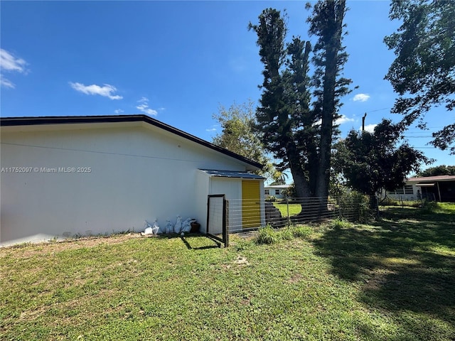 view of side of home with fence and a lawn