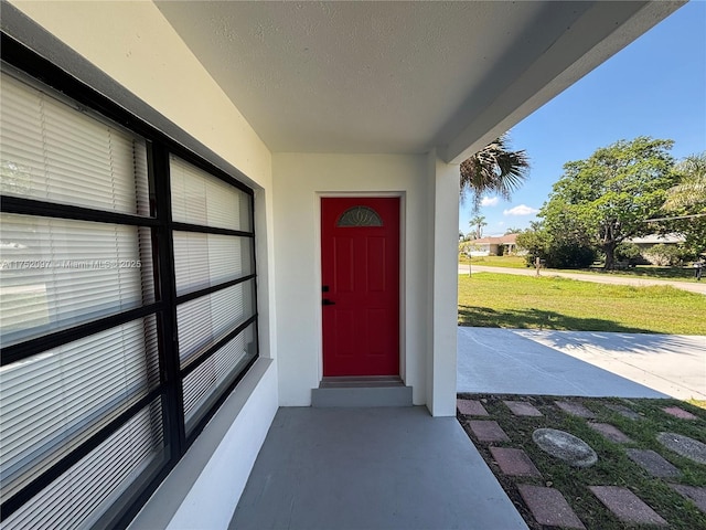 entrance to property with a lawn and stucco siding