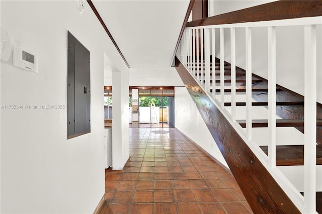 corridor featuring tile patterned floors, electric panel, and stairs