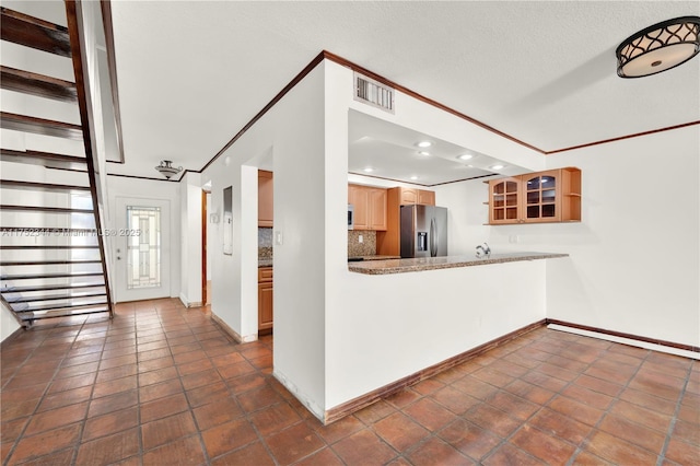 kitchen with visible vents, decorative backsplash, stainless steel fridge, glass insert cabinets, and crown molding