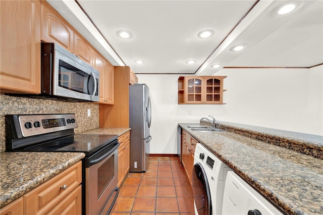 kitchen with backsplash, washer / clothes dryer, stainless steel appliances, and a sink