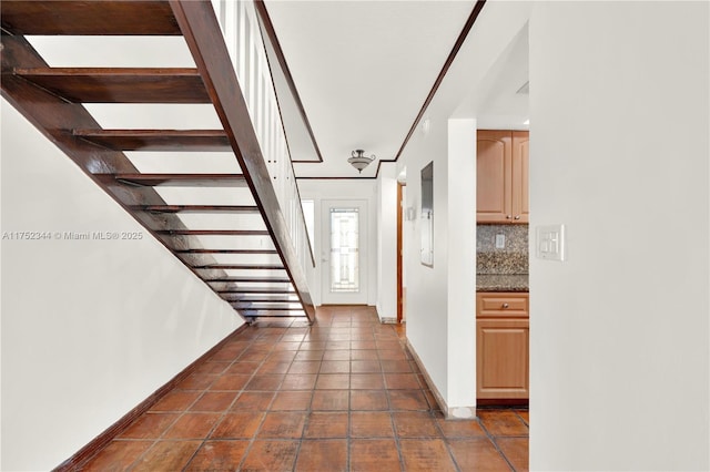 entrance foyer featuring dark tile patterned floors, stairs, and baseboards