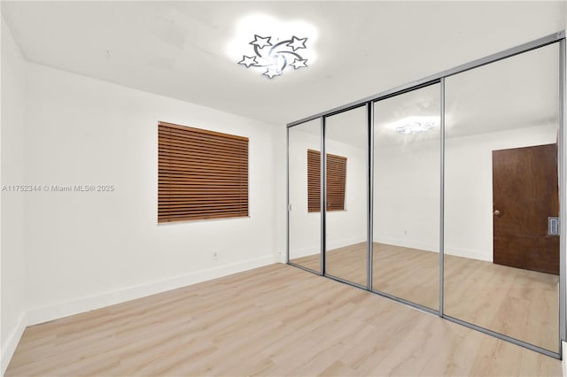 unfurnished bedroom featuring a closet, wood finished floors, and baseboards