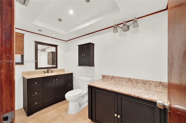 bathroom with a tray ceiling, visible vents, toilet, vanity, and tile patterned floors