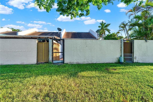 back of property with a gate, a yard, and stucco siding