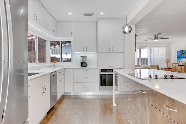 kitchen with white cabinetry, appliances with stainless steel finishes, light countertops, and decorative light fixtures