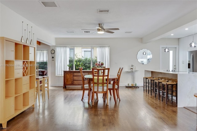 dining space with a ceiling fan, visible vents, baseboards, and wood finished floors