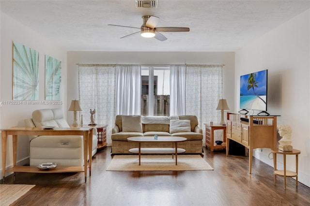 living room with visible vents, dark wood-type flooring, a textured ceiling, and a ceiling fan