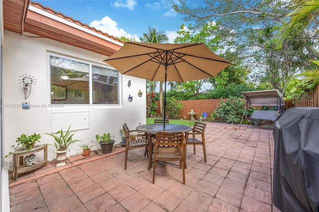 view of patio with outdoor dining area, grilling area, and fence