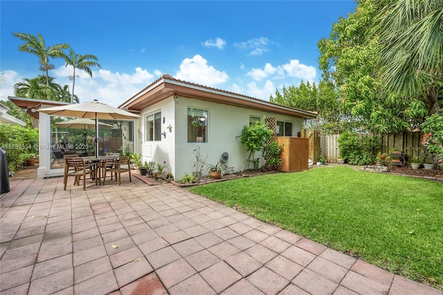 back of house featuring a patio area, a yard, fence, and stucco siding