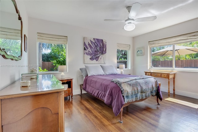 bedroom featuring dark wood-style floors, a ceiling fan, and baseboards