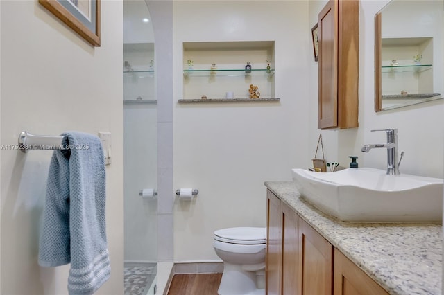 bathroom with a shower, vanity, toilet, and wood finished floors