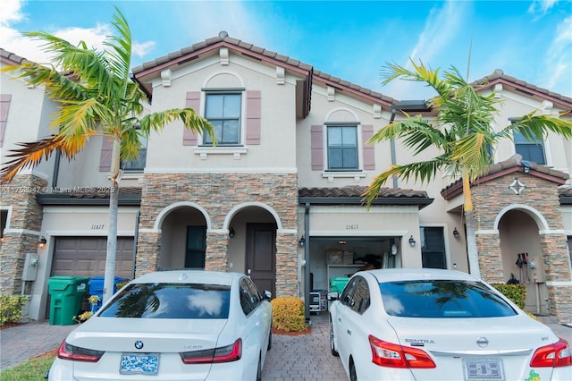 view of front of home featuring decorative driveway, an attached garage, a tile roof, and stucco siding