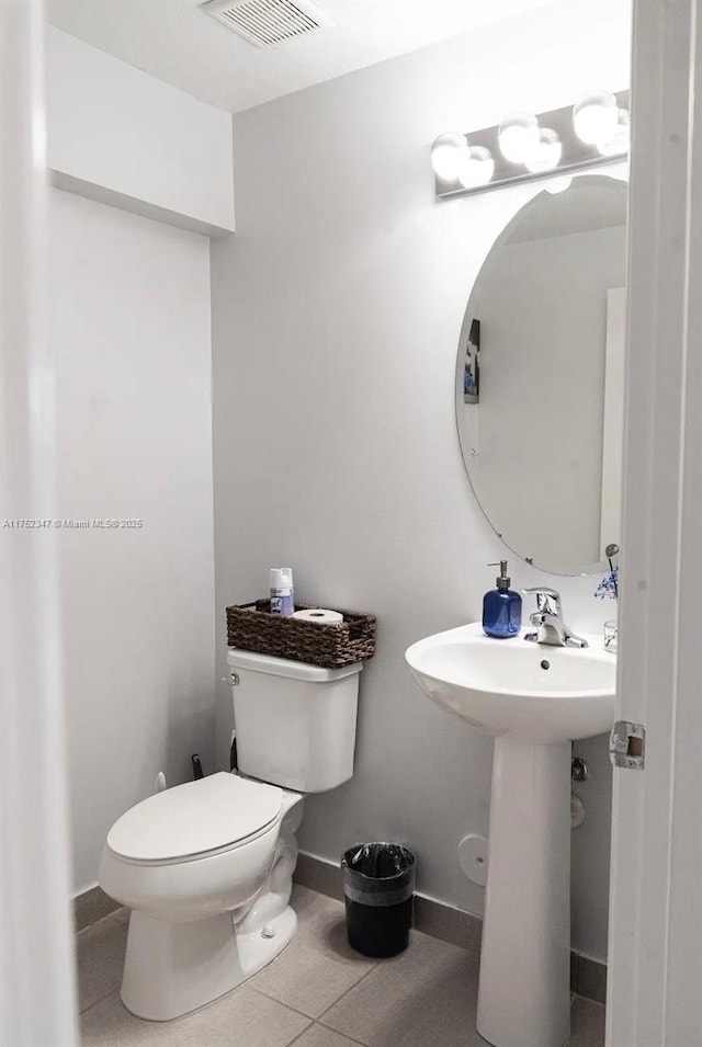 half bath with toilet, baseboards, visible vents, and tile patterned floors