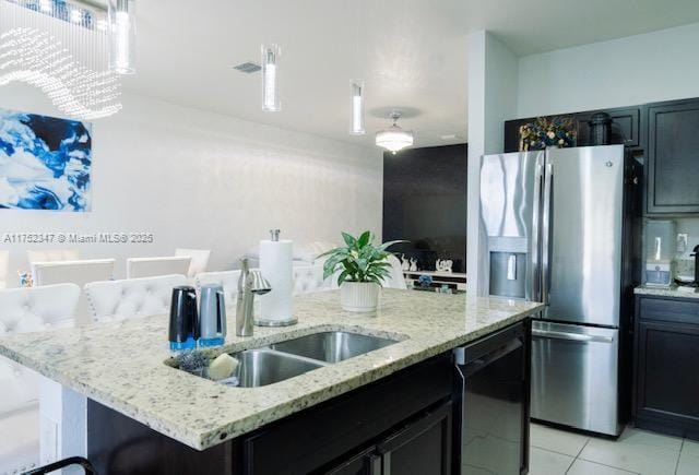 kitchen with dishwasher, light stone countertops, a kitchen island with sink, stainless steel refrigerator with ice dispenser, and a sink