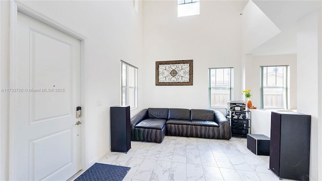 living room with marble finish floor, a towering ceiling, and a wealth of natural light