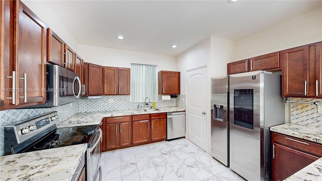 kitchen with marble finish floor, stainless steel appliances, decorative backsplash, a sink, and light stone countertops