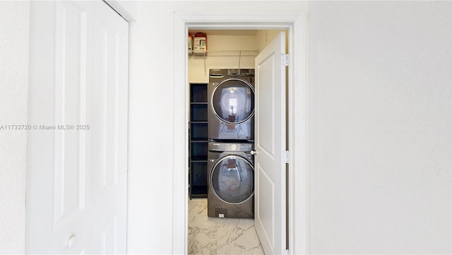 laundry area featuring marble finish floor, laundry area, and stacked washer / dryer