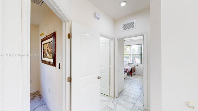 corridor with marble finish floor, visible vents, and baseboards