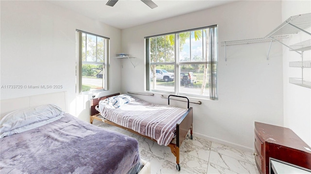 bedroom featuring ceiling fan, marble finish floor, and baseboards