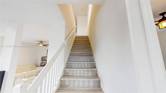 stairway featuring ceiling fan and wood finished floors