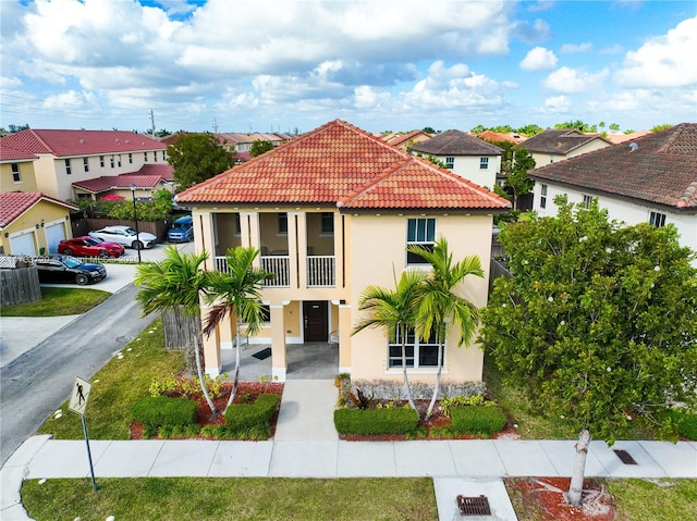 mediterranean / spanish home featuring a balcony, a tile roof, a residential view, and stucco siding