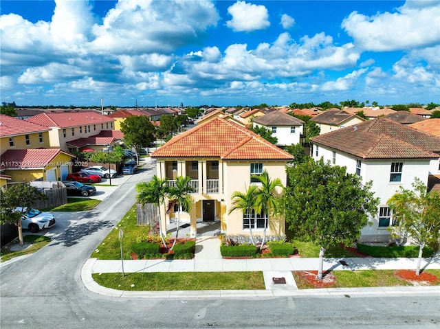 view of front facade featuring a balcony, a tiled roof, driveway, a residential view, and stucco siding