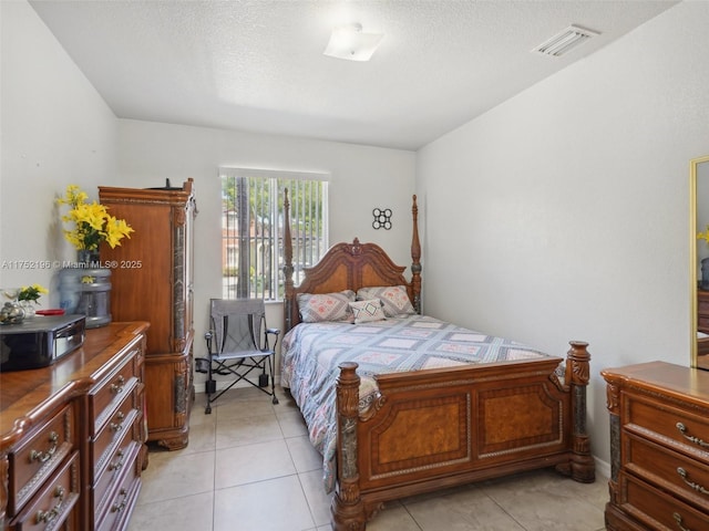 bedroom featuring light tile patterned floors, visible vents, and a textured ceiling