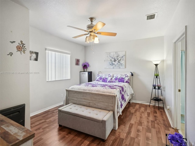 bedroom featuring dark wood-style floors, baseboards, visible vents, and a ceiling fan