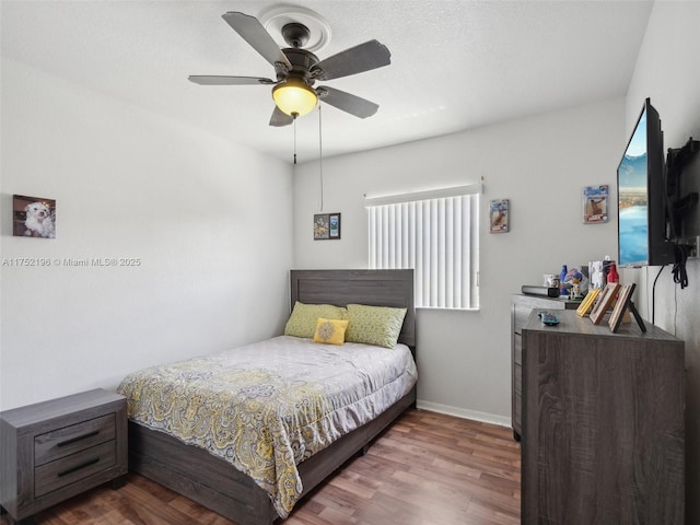 bedroom with dark wood finished floors, a ceiling fan, and baseboards