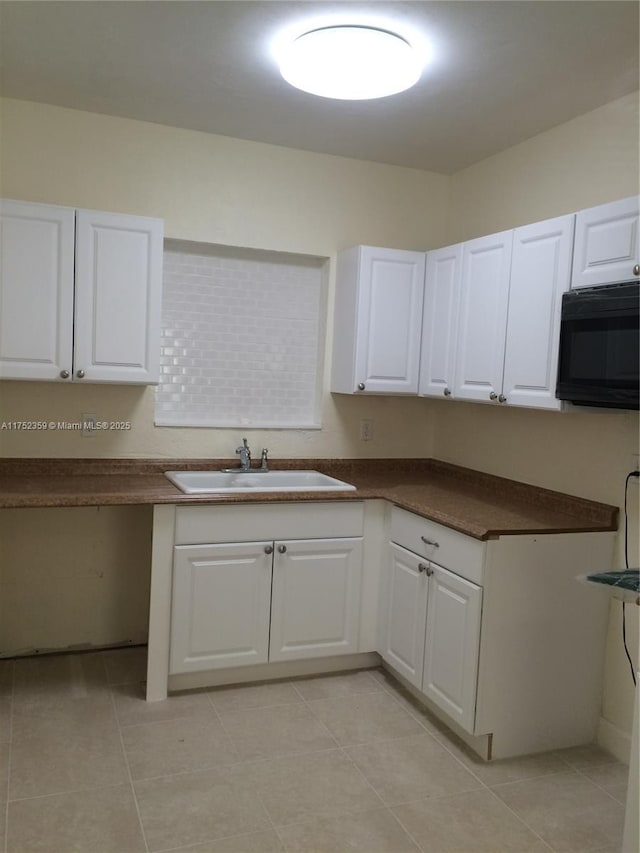 kitchen with dark countertops, black microwave, white cabinets, and a sink