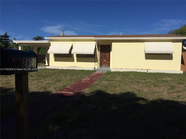 view of front of house featuring a carport, a front lawn, and stucco siding