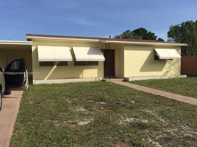 exterior space with brick siding, a lawn, an attached carport, and stucco siding