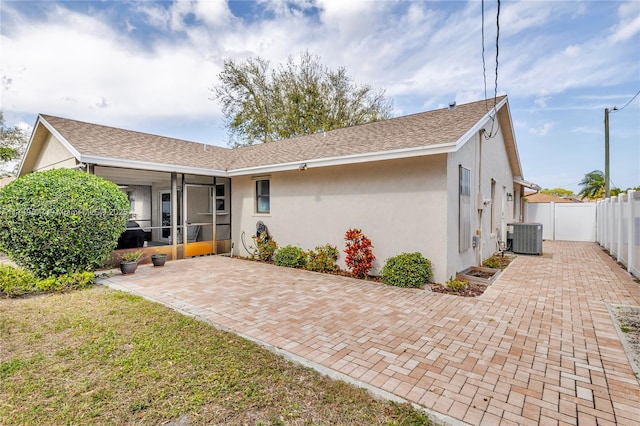 back of property featuring roof with shingles, stucco siding, a sunroom, fence, and cooling unit