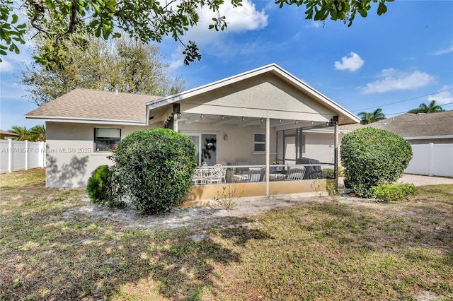 rear view of house featuring fence, a sunroom, and stucco siding