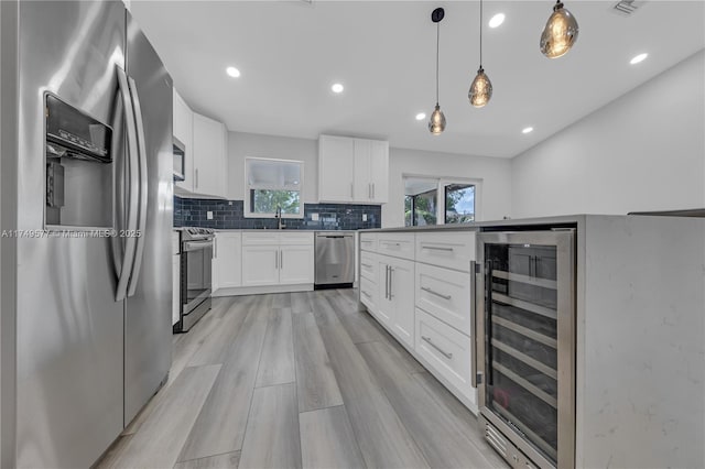 kitchen with wine cooler, pendant lighting, a wealth of natural light, appliances with stainless steel finishes, and white cabinets